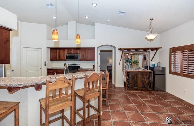 kitchen with visible vents, baseboards, a breakfast bar area, arched walkways, and stainless steel appliances