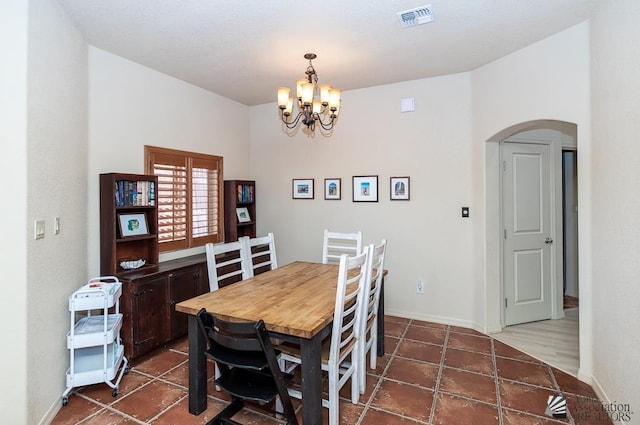dining room with arched walkways, baseboards, a chandelier, and visible vents