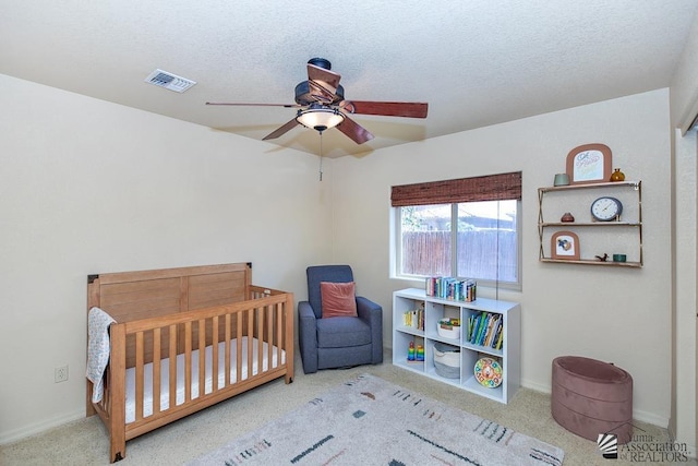 carpeted bedroom with a nursery area, ceiling fan, visible vents, and baseboards