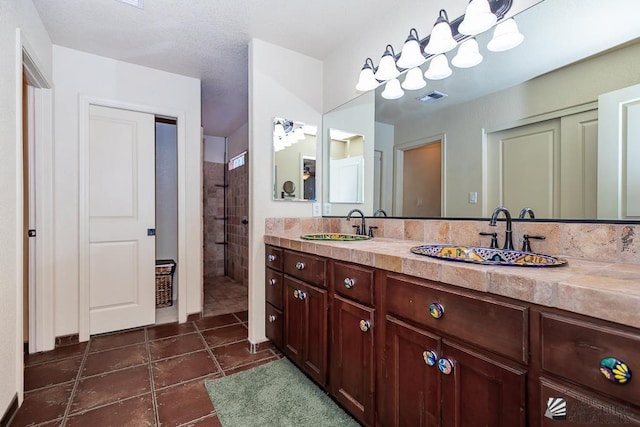 bathroom with double vanity, tile patterned floors, visible vents, and a sink