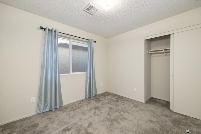 unfurnished bedroom featuring light carpet, a closet, and a textured ceiling