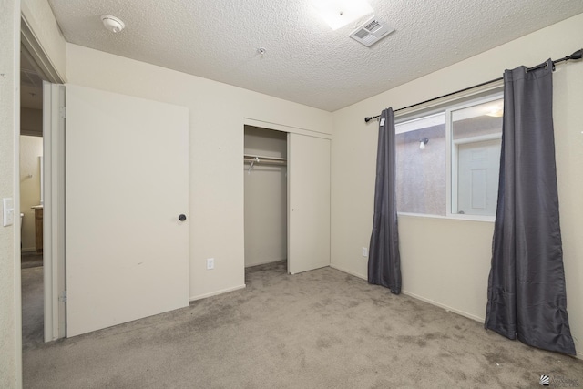 unfurnished bedroom with light colored carpet, a closet, and a textured ceiling