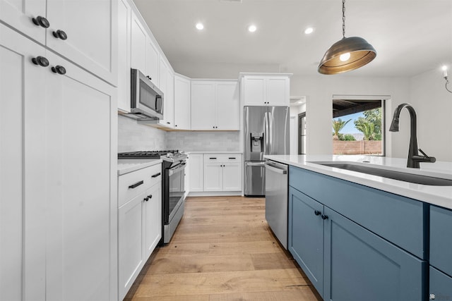 10369 S Fairway Loop, Yuma, AZ 85367 - kitchen featuring stainless steel appliances, blue cabinets, light wood finished floors, light countertops, and backsplash