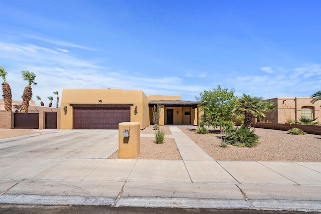 10369 S Fairway Loop, Yuma, AZ 85367 - pueblo-style house with concrete driveway, an attached garage, stucco siding, and a gate