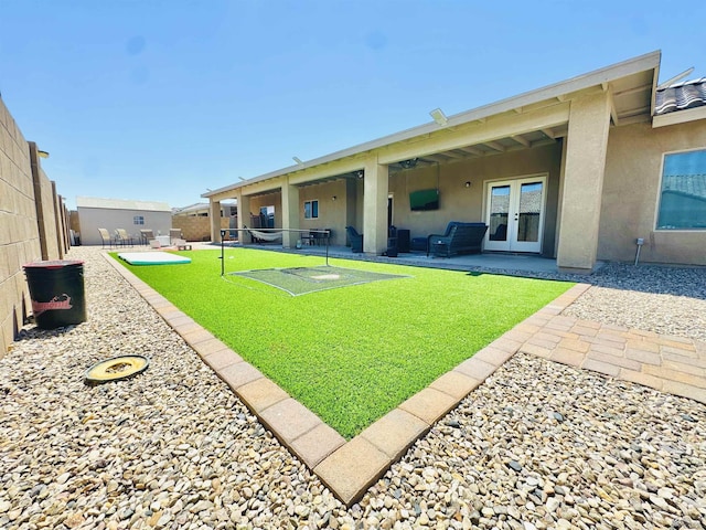 back of house featuring a fenced backyard, stucco siding, french doors, a patio area, and a lawn