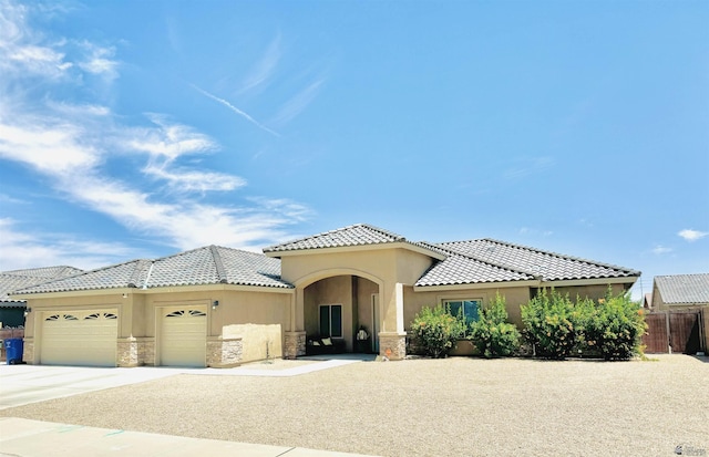 mediterranean / spanish house featuring an attached garage, stucco siding, a tiled roof, and concrete driveway