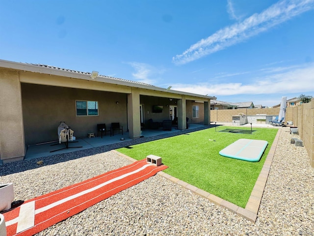 back of property with a fenced backyard, stucco siding, a yard, and a patio area