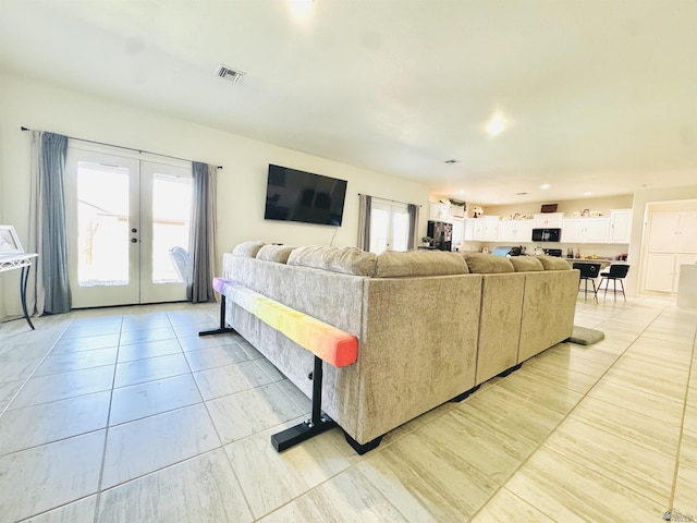 living room featuring a healthy amount of sunlight, light tile patterned floors, french doors, and visible vents