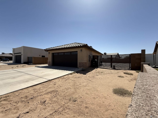 126 N Joe Harper Ct, San Luis, AZ 85349 - view of front facade with a gate, concrete driveway, an attached garage, a tile roof, and stone siding