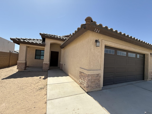 126 N Joe Harper Ct, San Luis, AZ 85349 - view of front facade with stone siding, a garage, stucco siding, a tile roof, and driveway