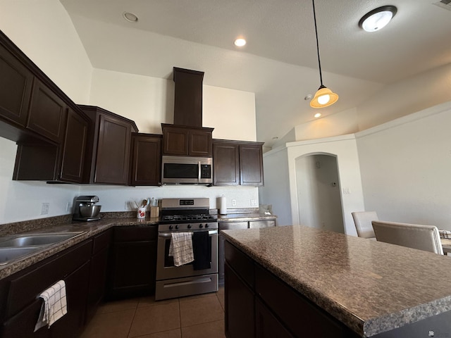 126 N Joe Harper Ct, San Luis, AZ 85349 - kitchen featuring stainless steel appliances, dark countertops, arched walkways, tile patterned floors, and lofted ceiling