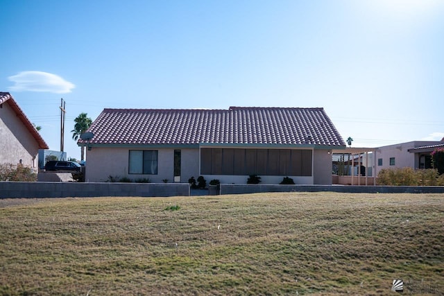 back of property featuring a lawn and a tiled roof