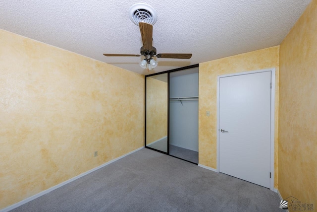 unfurnished bedroom with a textured ceiling, carpet floors, visible vents, a ceiling fan, and a closet