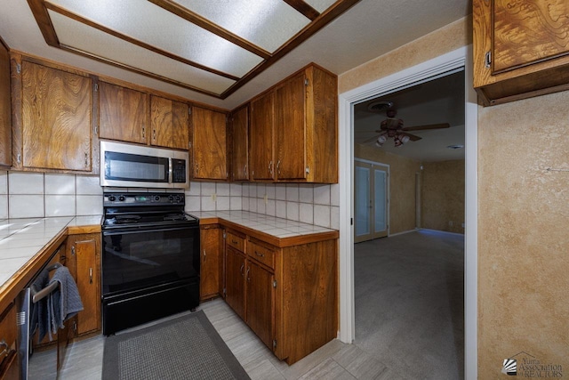 kitchen with appliances with stainless steel finishes, brown cabinets, and tile counters