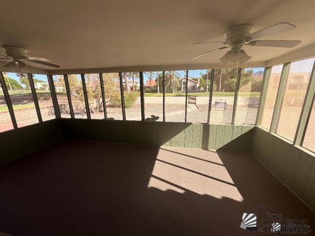 unfurnished sunroom with ceiling fan