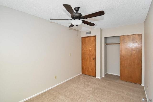 unfurnished bedroom featuring ceiling fan, a closet, light colored carpet, and a textured ceiling