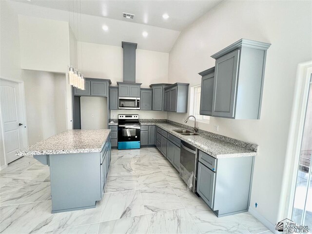 kitchen featuring appliances with stainless steel finishes, gray cabinetry, sink, high vaulted ceiling, and a kitchen island