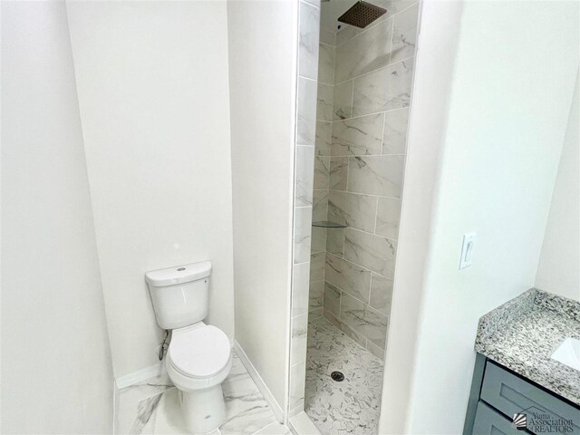 bathroom with vanity, toilet, and tiled shower