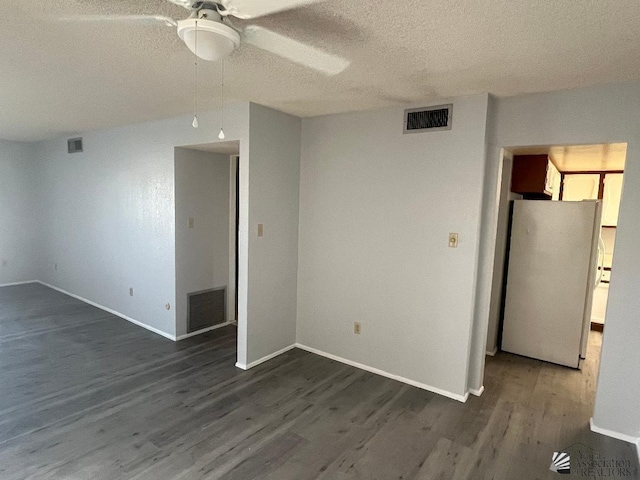 unfurnished room with a textured ceiling, dark wood-type flooring, and ceiling fan