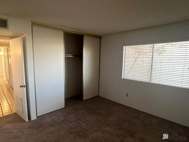 unfurnished bedroom with dark carpet and a closet