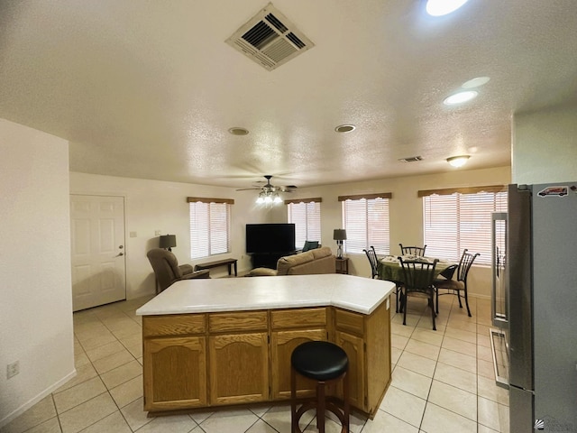 kitchen featuring freestanding refrigerator, light tile patterned flooring, open floor plan, and visible vents