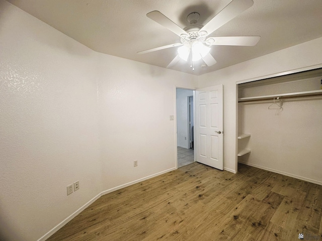 unfurnished bedroom featuring baseboards, ceiling fan, wood finished floors, and a closet