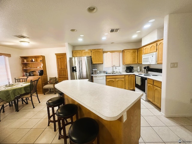 kitchen featuring visible vents, light tile patterned flooring, white appliances, light countertops, and a sink