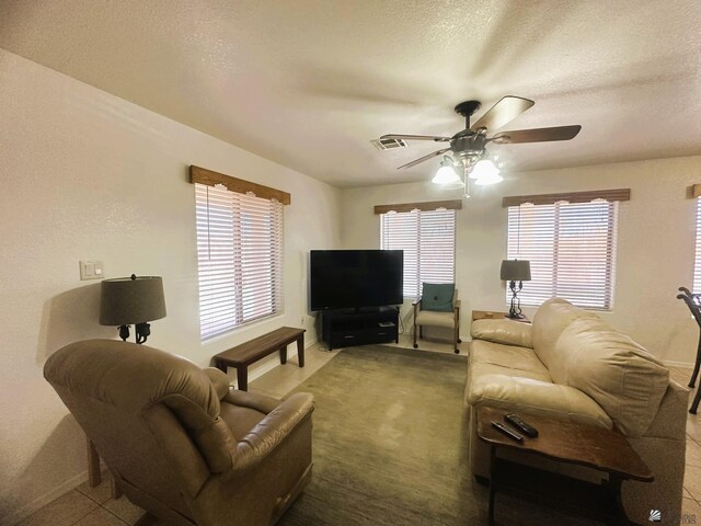 living area featuring baseboards, ceiling fan, and visible vents