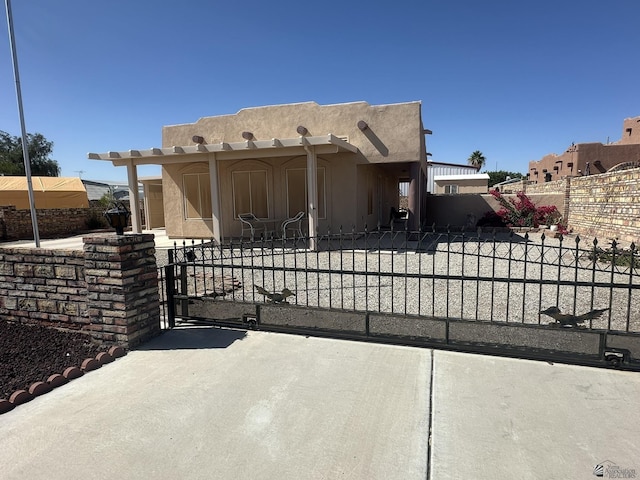 southwest-style home with a fenced front yard, a gate, and stucco siding