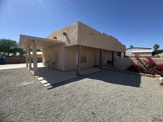 rear view of house featuring a patio and stucco siding