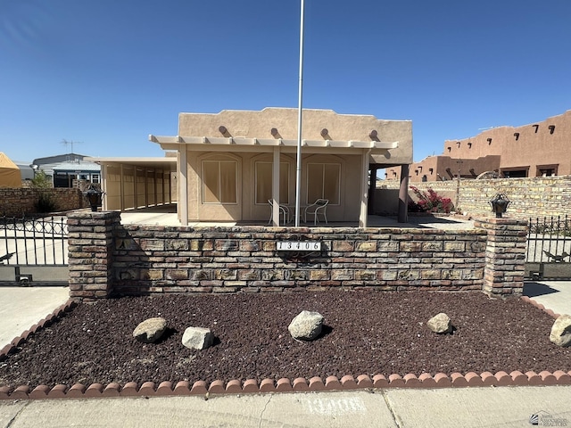 view of front of property with stucco siding, fence, and a patio