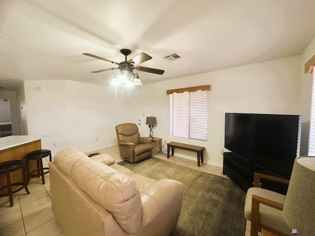 living area featuring light tile patterned floors, ceiling fan, and visible vents