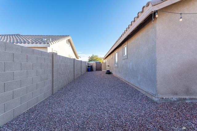 view of side of home with a fenced backyard and stucco siding