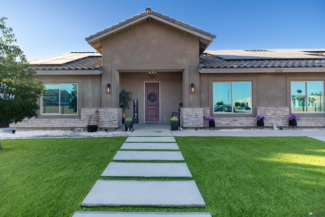 5712 E 45th Pl, Yuma, AZ 85365 - view of front of home featuring stone siding, solar panels, a tile roof, and a front lawn