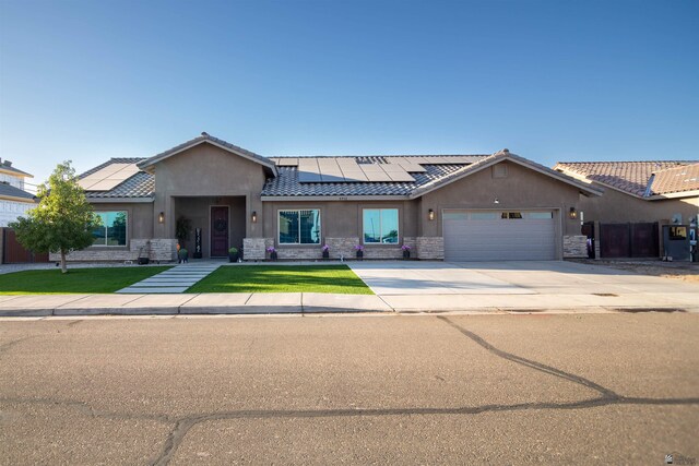 5712 E 45th Pl, Yuma, AZ 85365 - single story home with stone siding, solar panels, a garage, stucco siding, and driveway
