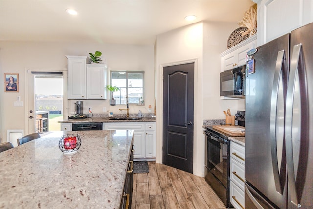 5712 E 45th Pl, Yuma, AZ 85365 - kitchen featuring black appliances, a sink, white cabinetry, light wood-type flooring, and light stone counters