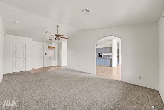unfurnished living room with ceiling fan, visible vents, carpet floors, arched walkways, and vaulted ceiling