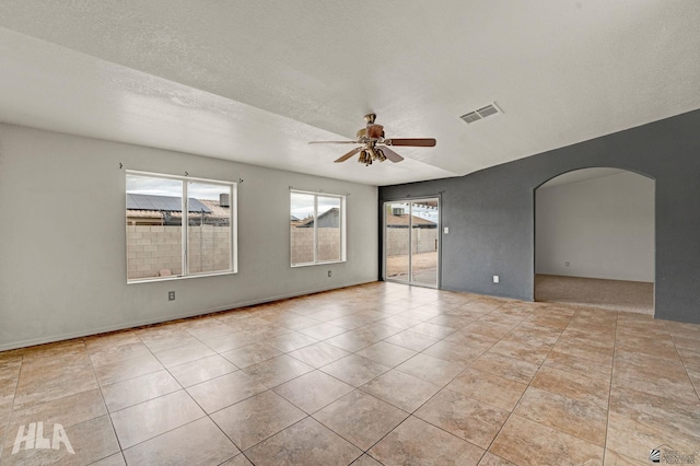 tiled spare room featuring arched walkways, ceiling fan, and visible vents
