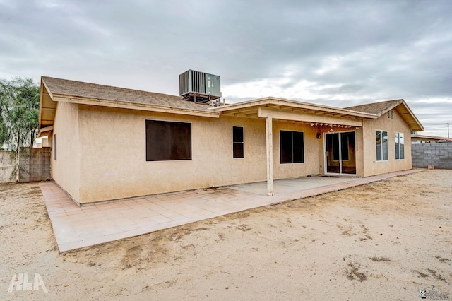 rear view of property featuring a patio, fence, central AC unit, and stucco siding