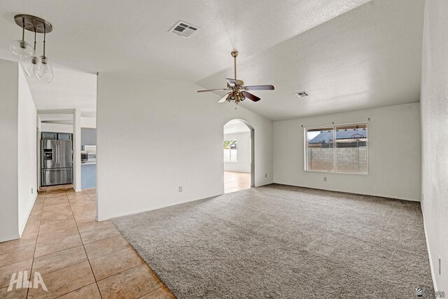 spare room with visible vents, light tile patterned flooring, arched walkways, a ceiling fan, and vaulted ceiling