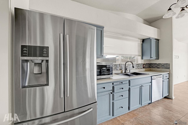 kitchen featuring gray cabinets, backsplash, appliances with stainless steel finishes, a sink, and light countertops