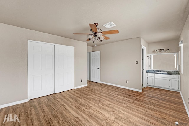 unfurnished bedroom with visible vents, a closet, baseboards, a sink, and light wood-style flooring