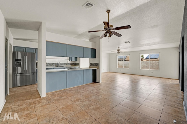 kitchen with a sink, a ceiling fan, open floor plan, stainless steel refrigerator with ice dispenser, and visible vents