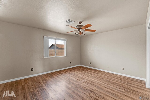 empty room featuring baseboards, ceiling fan, wood finished floors, and visible vents