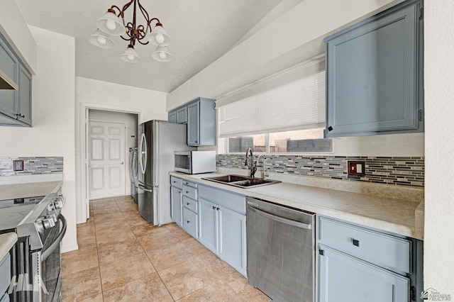 kitchen featuring a notable chandelier, a sink, light countertops, stainless steel appliances, and backsplash