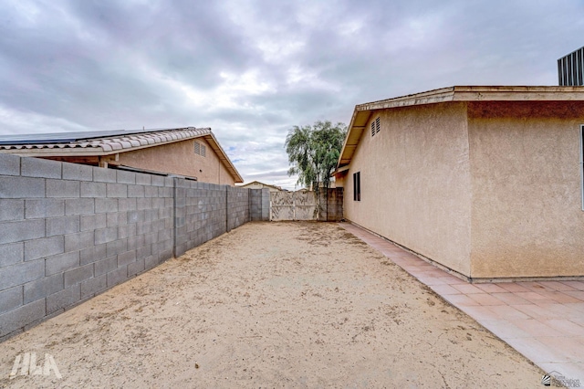 view of side of home with stucco siding and fence