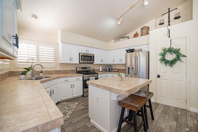 4031 W 16th Pl, Yuma, AZ 85364 - kitchen featuring appliances with stainless steel finishes, a sink, a kitchen breakfast bar, white cabinetry, and lofted ceiling