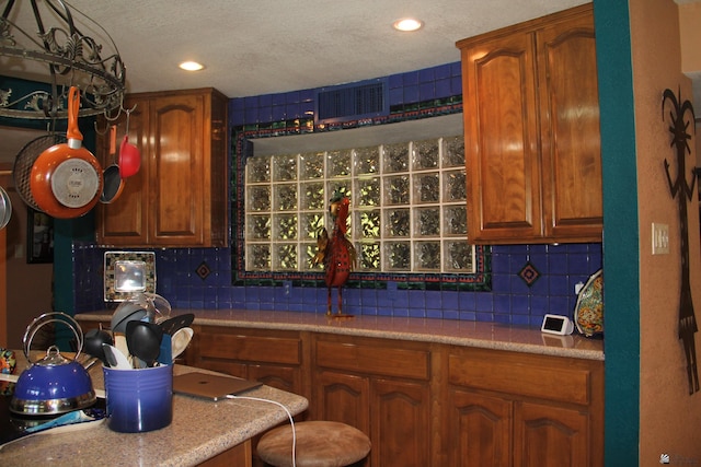 1936 W 15th Pl, Yuma, AZ 85364 - kitchen featuring backsplash, light countertops, brown cabinets, a textured ceiling, and recessed lighting