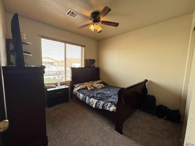 bedroom featuring ceiling fan, dark carpet, a textured ceiling, and visible vents