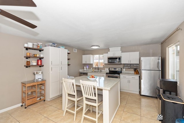 kitchen with plenty of natural light, a sink, appliances with stainless steel finishes, and light tile patterned floors